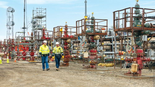 Two workers walking near rig equipment