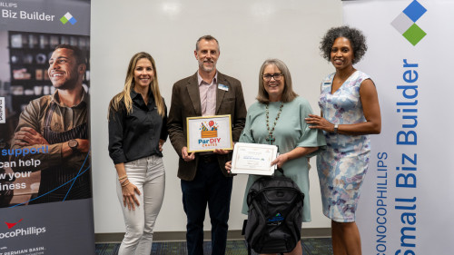 Two students holding up their graduation certificates.