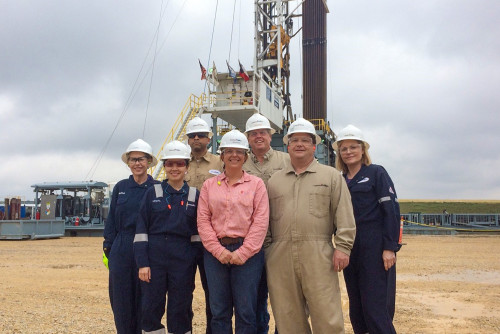Becky and crew in the field in front of a rig - Lower 48
