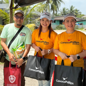 Three volunteers with ConocoPhillips bags helping with flood relief