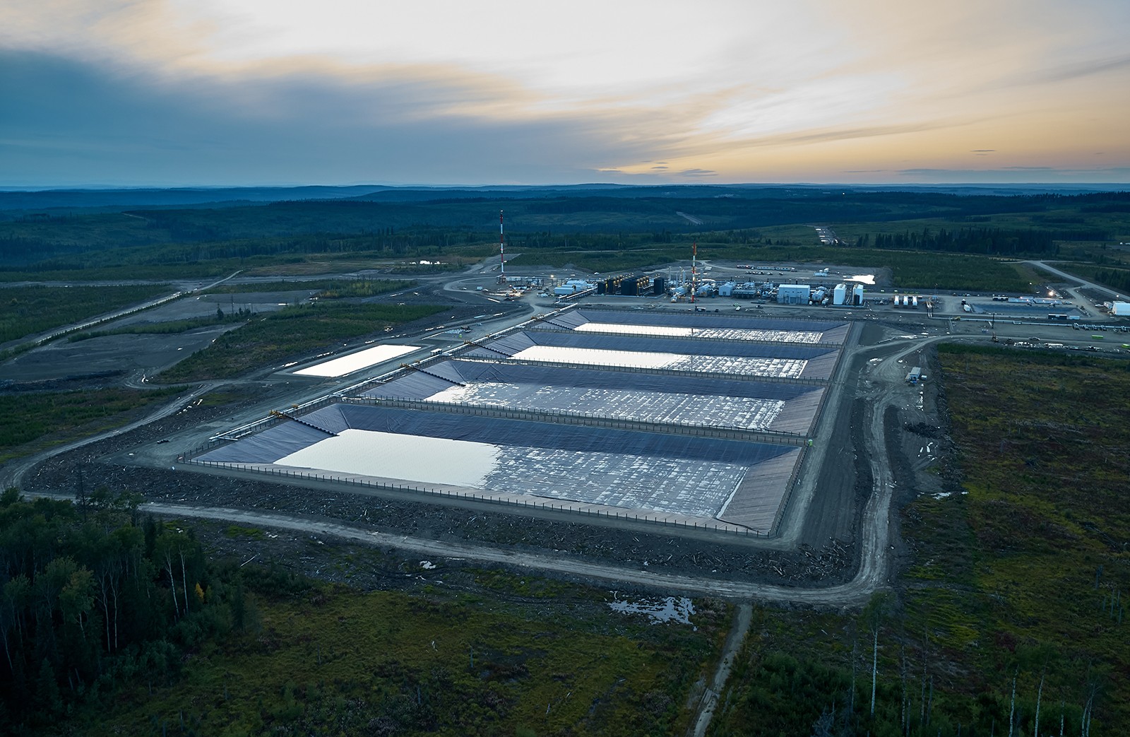 Aerial view of four holding ponds at dusk with green landscape surrounding.