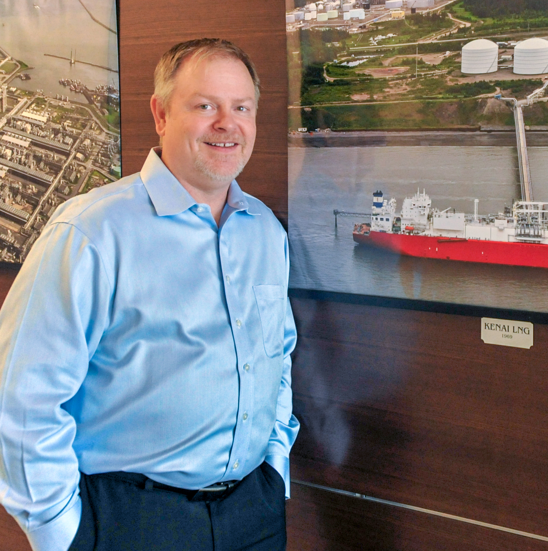 Darren Meznarich standing near wall with large photos of LNG locations 