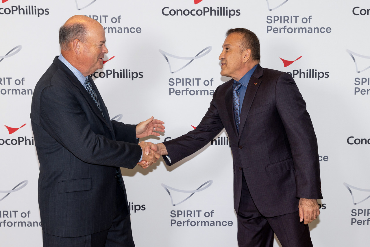 Ryan Lance shakes Dr. Adham's hand in front of SPIRIT Awards photo backdrop