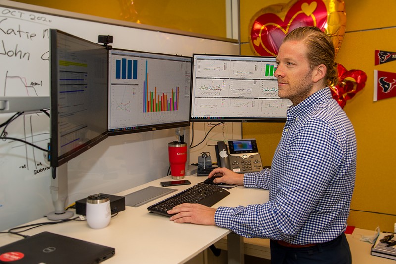 Bjoernar Nesland in office setting standing at desk looking at one of three computer screens