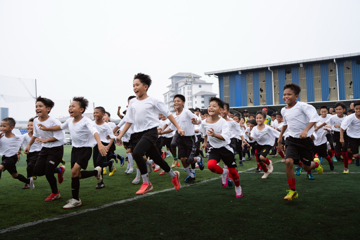A large group of very excited young boys running across a football field