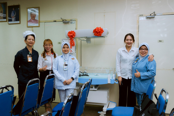 Five nurses smiling standing in a hospital