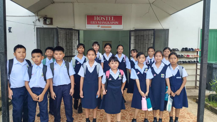 A large group of students in uniforms standing in front of a hostel