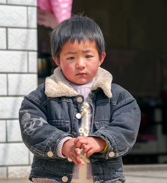 Wenwen as a young child, outdoors wearing denim jacket