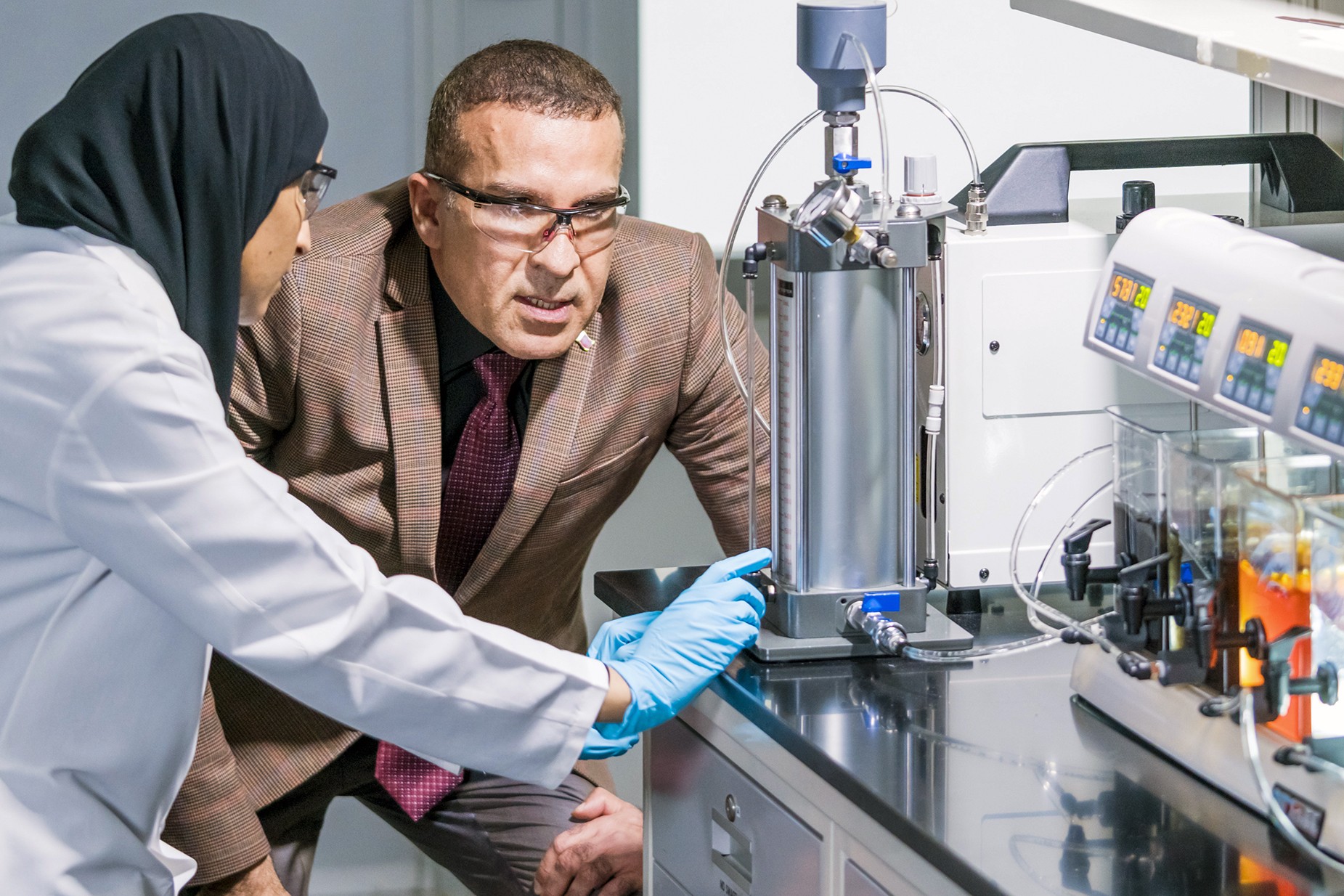 Mashael Al-Maas and Samer Adham looking at testing equipment in laboratory