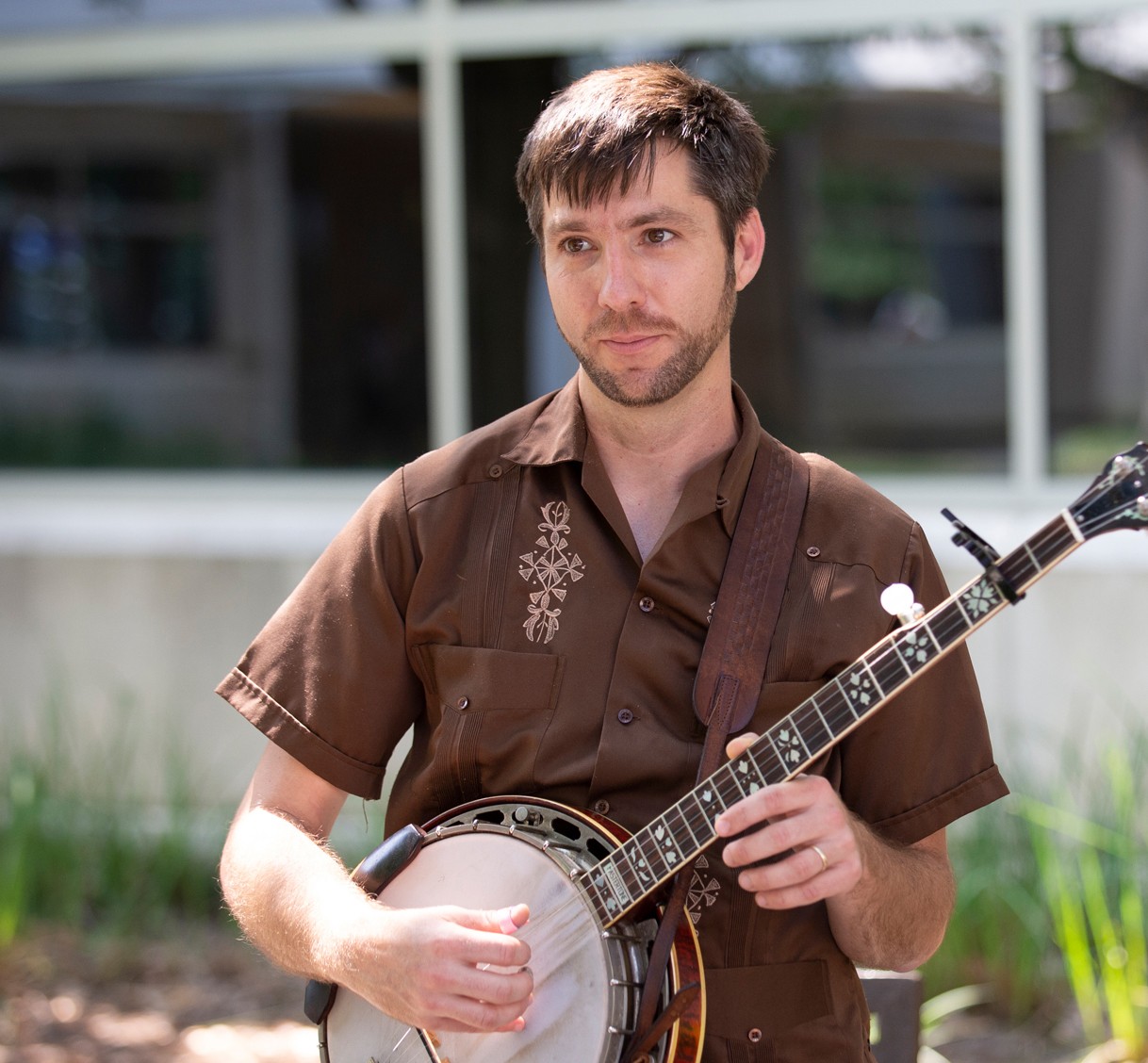 John Templeton outdoors at campus strumming banjo