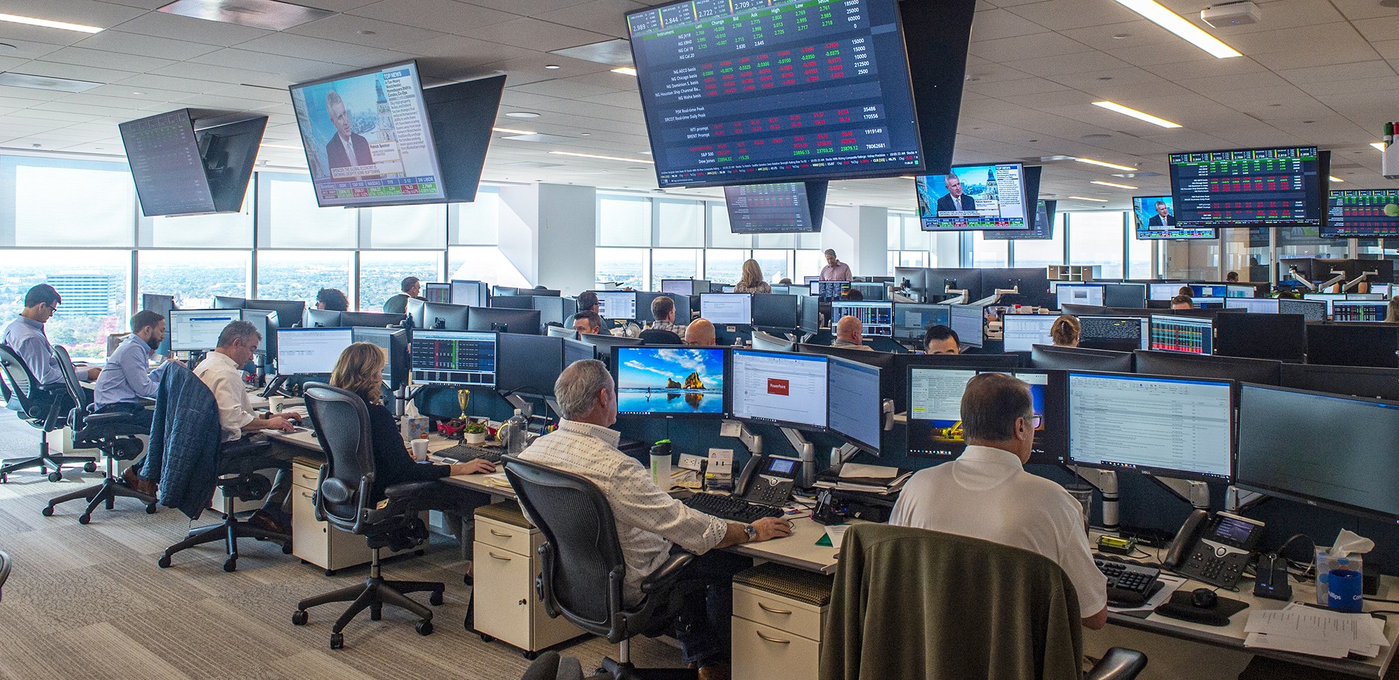 Commercial floor - room with workers at computers and ceiling monitors