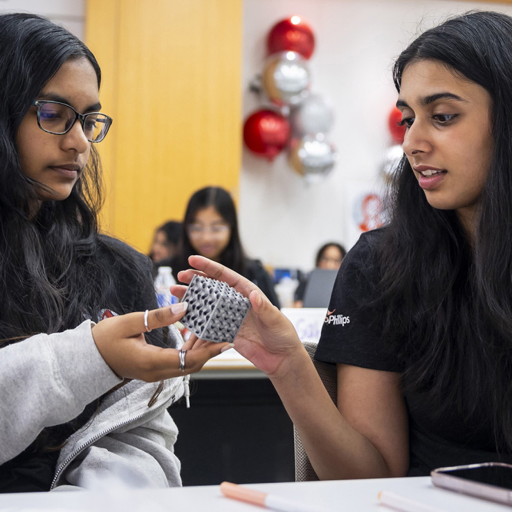 Jordan High School seniors Ananya Loke, left, and Kavya Malgi, daughter of ConocoPhillips Analytics Platforms Staff Architect Anand Malgi, examine a 3D-printed aluminum cube provided by the ConocoPhillips Emerging Digital Technology group. 