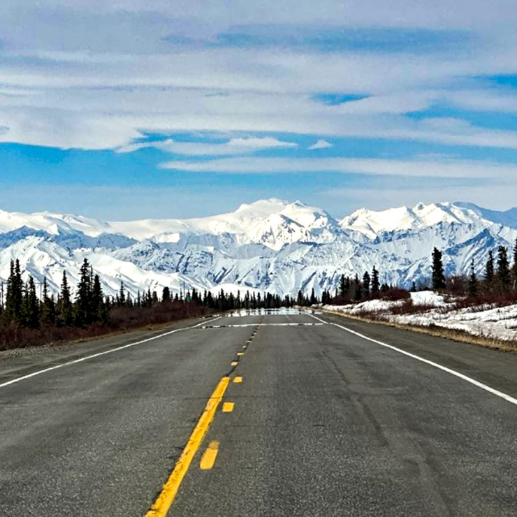 A view of the open road in Alaska with the mountains in the distance
