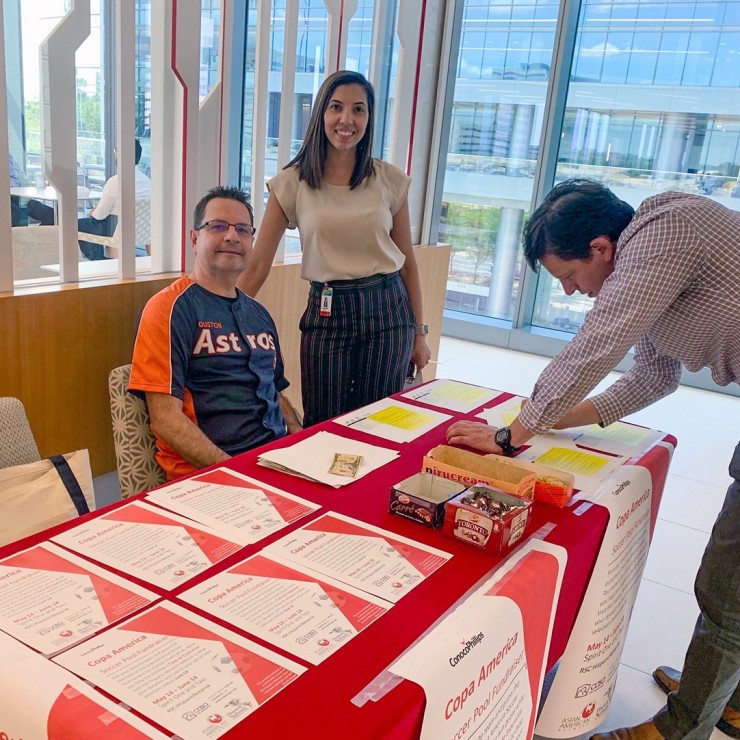 PHOTO: Hispanic Network member Jose Delgado, left, registers Claudia Avila and Jakovs Itkins for the 2019 Copa America fundraiser. 