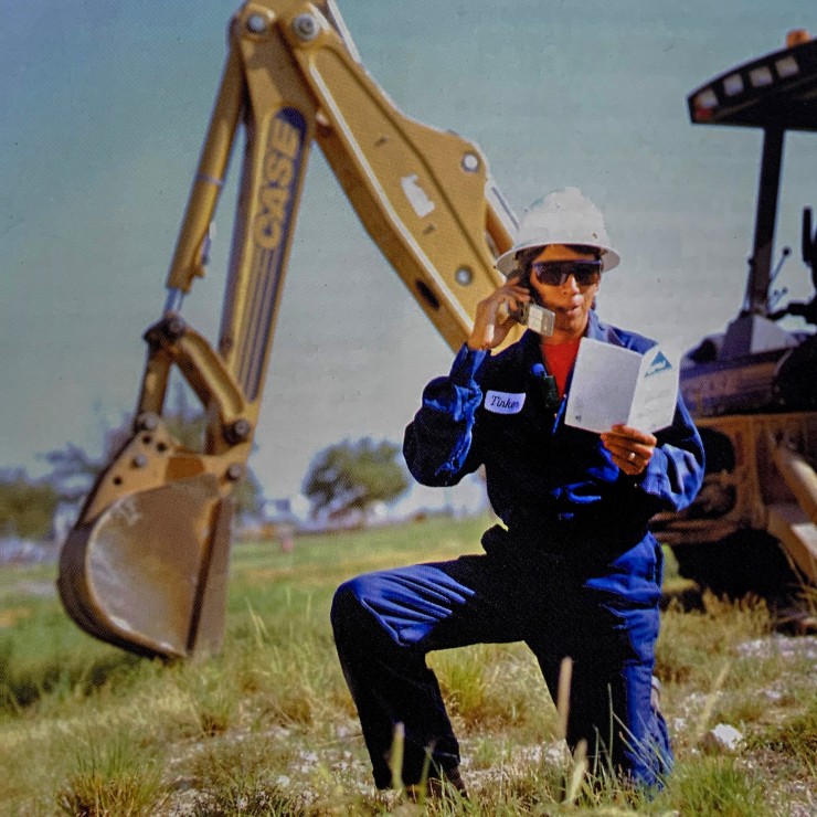 Tinker in the field on a cellphone reading a manual